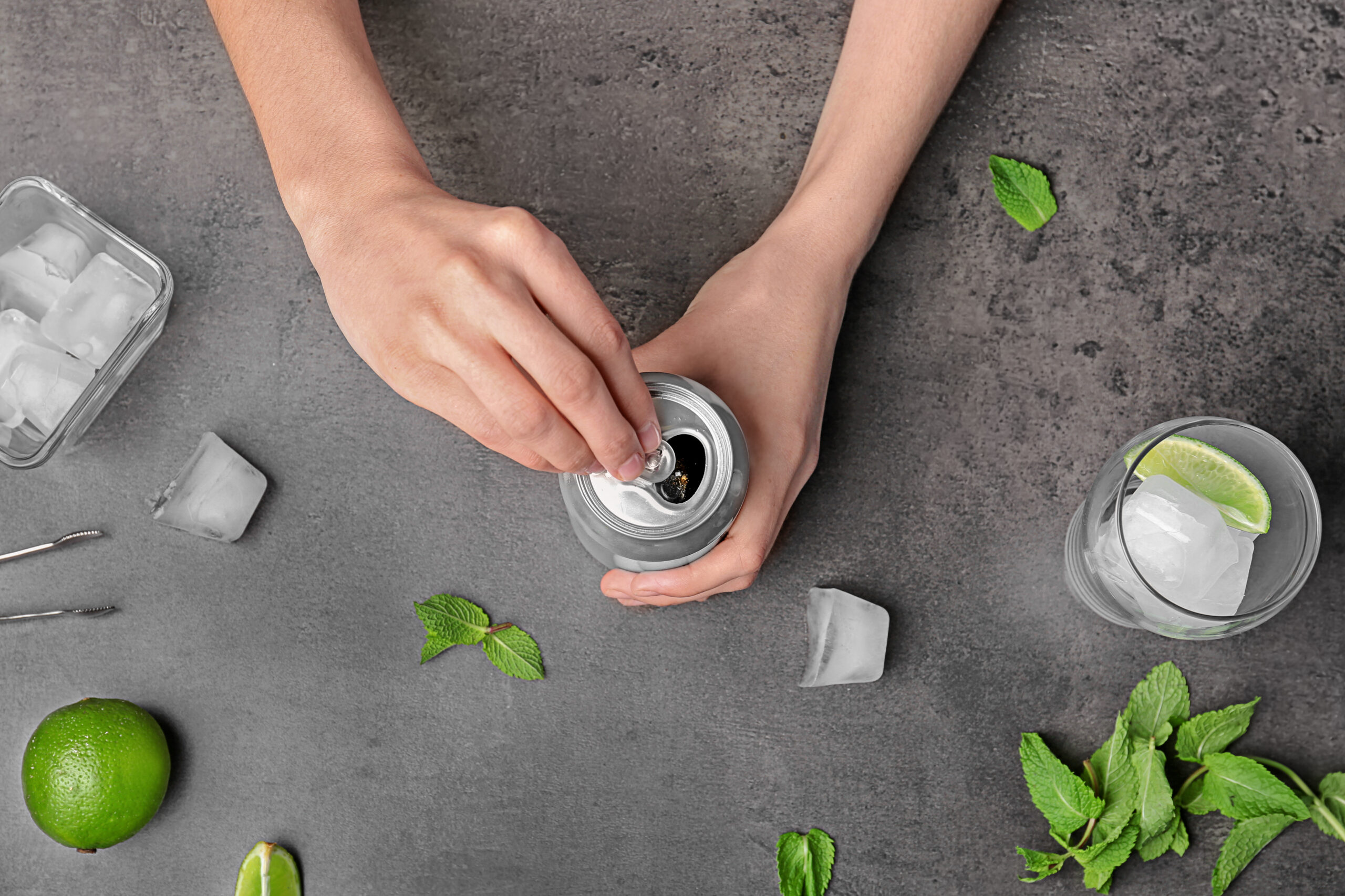 Woman with tin can of beverage at table, top view